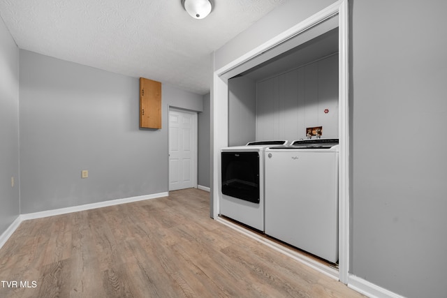 laundry area with light hardwood / wood-style floors, washer and dryer, and a textured ceiling