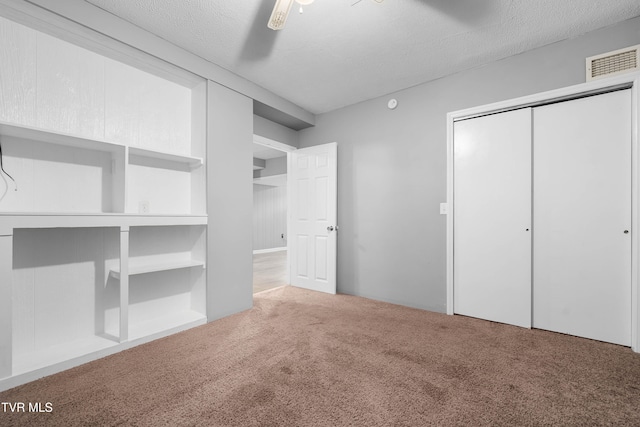 unfurnished bedroom featuring a textured ceiling, carpet flooring, and ceiling fan