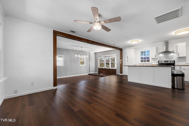 kitchen with white cabinets, stainless steel range with electric cooktop, a textured ceiling, dark wood-type flooring, and wall chimney exhaust hood