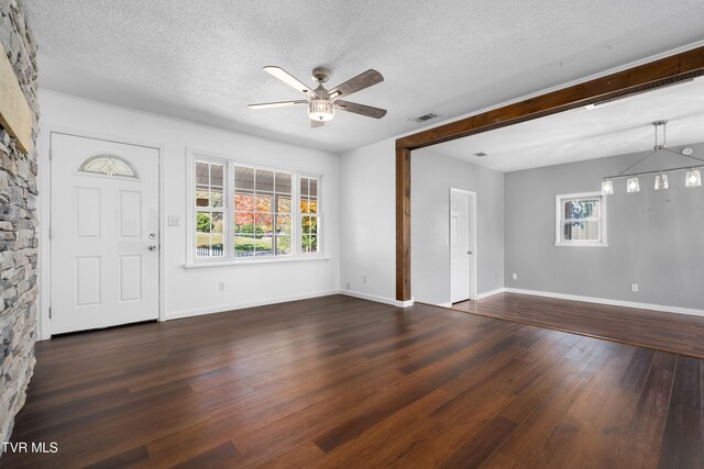 entrance foyer with a textured ceiling, a healthy amount of sunlight, dark wood-type flooring, and ceiling fan with notable chandelier