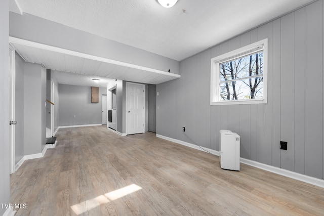 basement featuring light hardwood / wood-style flooring and wood walls