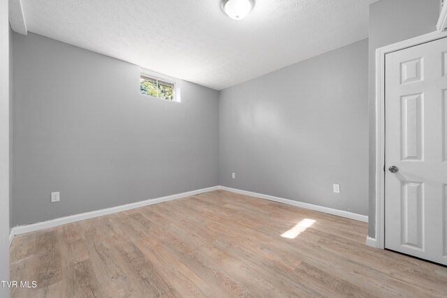 empty room with a textured ceiling and light hardwood / wood-style flooring