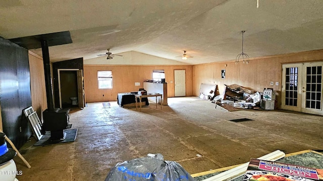 misc room with french doors, ceiling fan with notable chandelier, vaulted ceiling, and a wood stove