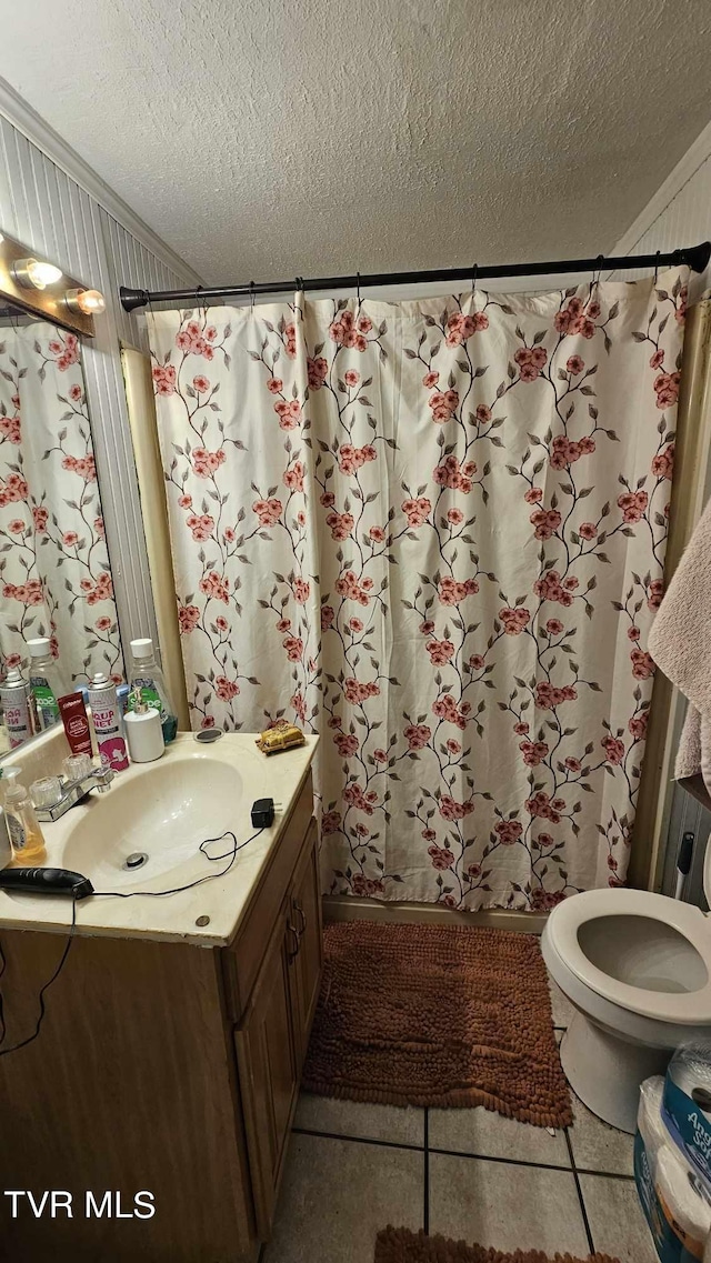 bathroom featuring vanity, toilet, a textured ceiling, and tile patterned floors