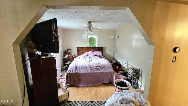 bedroom featuring ceiling fan, hardwood / wood-style flooring, crown molding, and a textured ceiling