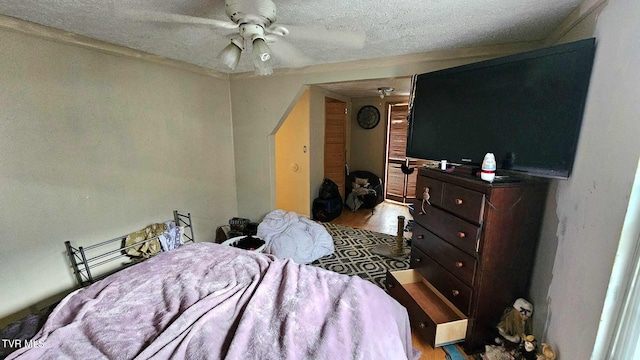 bedroom with ceiling fan, light hardwood / wood-style floors, and a textured ceiling