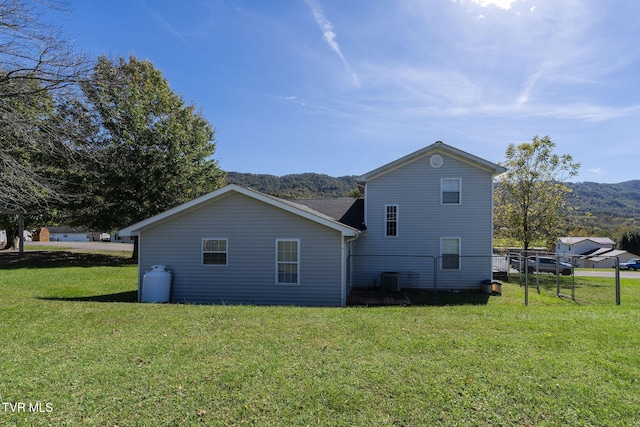 back of house with a mountain view and a lawn