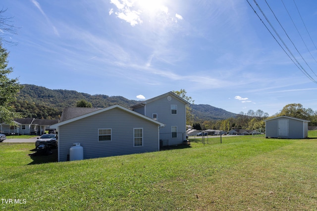 back of house with a mountain view, a storage shed, and a lawn