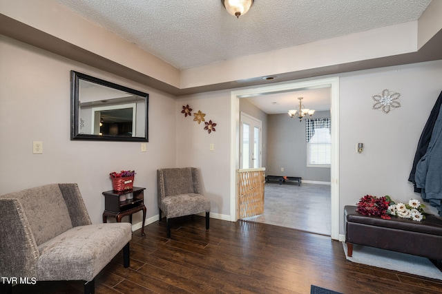 living area with a textured ceiling, a chandelier, and dark hardwood / wood-style flooring