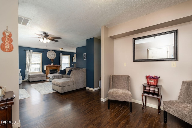 living room featuring dark wood-type flooring, a textured ceiling, and ceiling fan