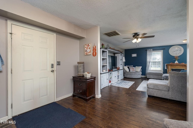 living area featuring visible vents, baseboards, ceiling fan, a textured ceiling, and wood-type flooring