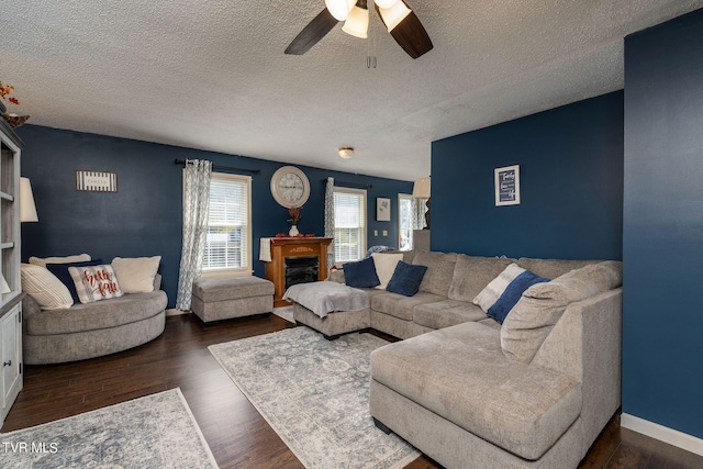 living room featuring ceiling fan, dark hardwood / wood-style floors, and a textured ceiling