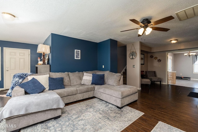 living room with stairway, a textured ceiling, visible vents, ceiling fan with notable chandelier, and wood finished floors