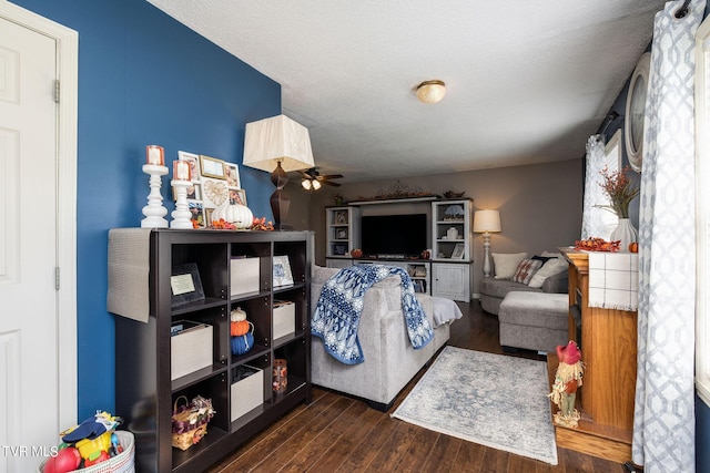 living room with a textured ceiling, a ceiling fan, and wood finished floors
