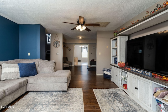 living room with ceiling fan, dark hardwood / wood-style flooring, and a textured ceiling