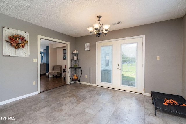 entryway featuring visible vents, baseboards, a chandelier, a textured ceiling, and french doors
