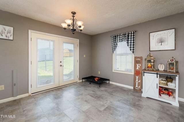 doorway to outside featuring french doors, a chandelier, and a textured ceiling