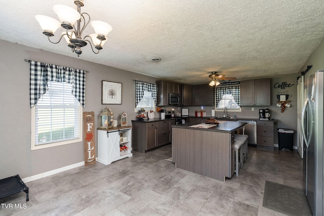 kitchen featuring a center island, sink, pendant lighting, appliances with stainless steel finishes, and a textured ceiling