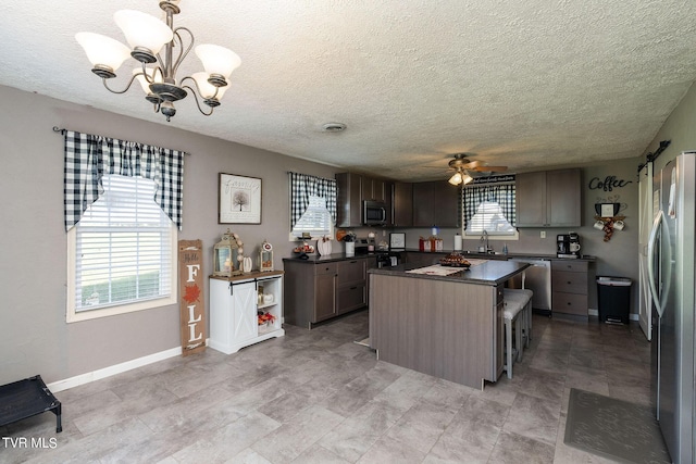 kitchen featuring dark countertops, a textured ceiling, appliances with stainless steel finishes, and a sink