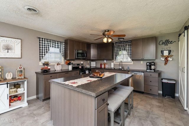 kitchen featuring ceiling fan, visible vents, dark countertops, a sink, and stainless steel appliances