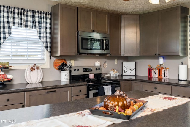 kitchen with a textured ceiling, appliances with stainless steel finishes, and dark countertops