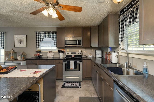 kitchen with dark countertops, plenty of natural light, a sink, and appliances with stainless steel finishes