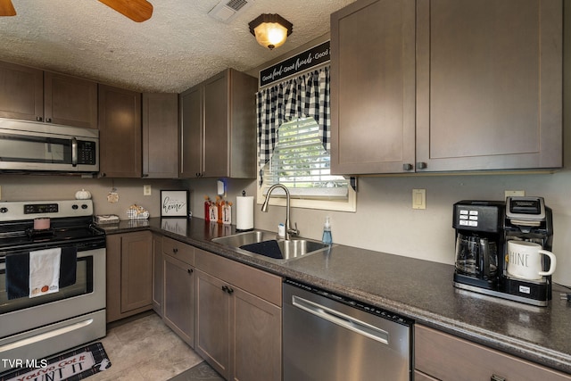 kitchen with ceiling fan, dark brown cabinetry, sink, appliances with stainless steel finishes, and a textured ceiling