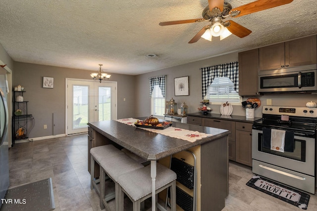 kitchen featuring a textured ceiling, a breakfast bar, a center island, dark countertops, and stainless steel appliances