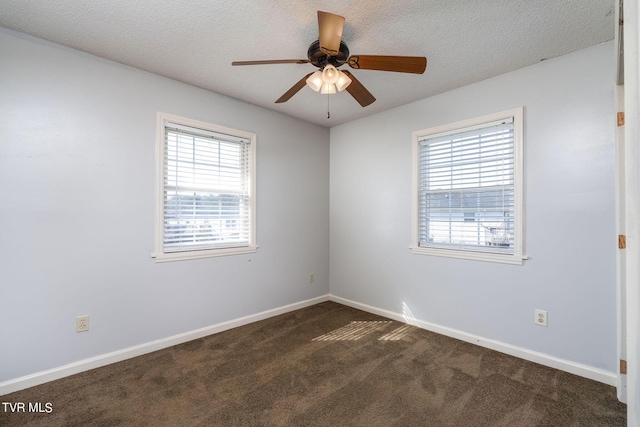spare room with dark carpet, baseboards, a ceiling fan, and plenty of natural light
