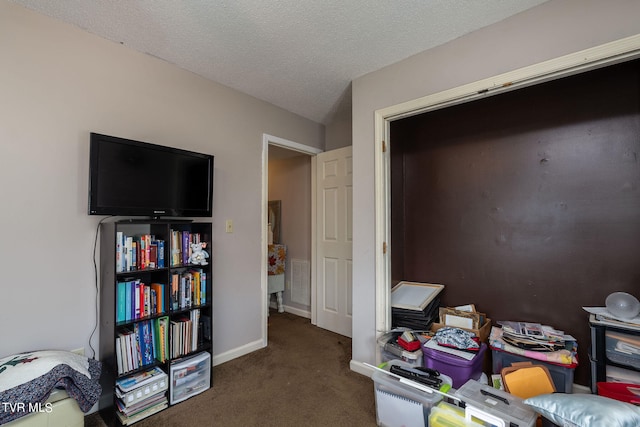 interior space featuring dark colored carpet and a textured ceiling