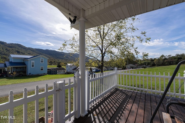 wooden deck with a mountain view and a lawn