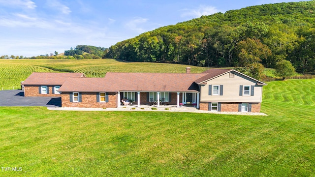 back of house featuring a rural view, a yard, and a patio area