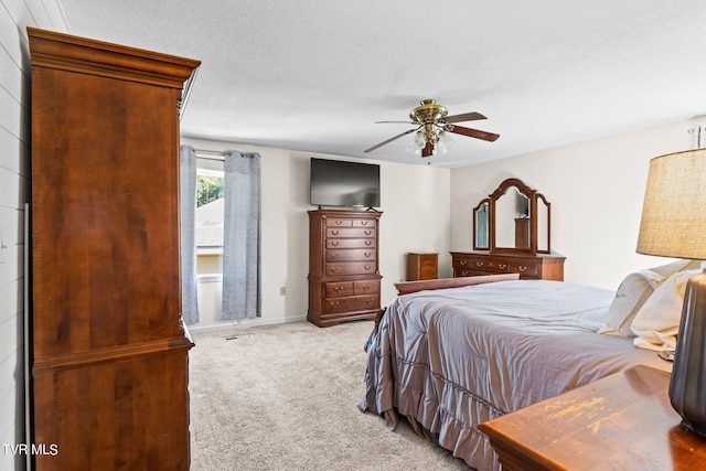 bedroom with light carpet, ceiling fan, and a textured ceiling