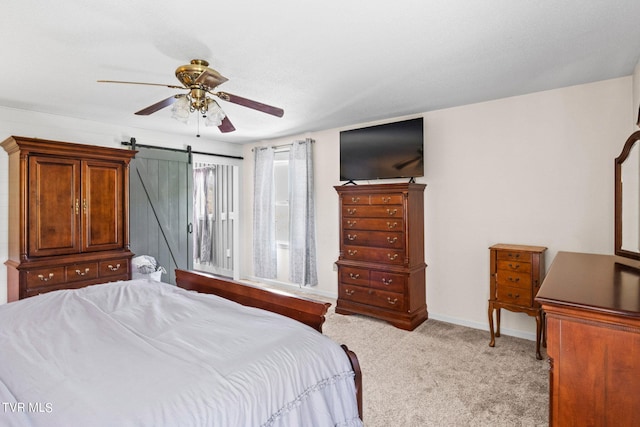 carpeted bedroom featuring ceiling fan and a barn door