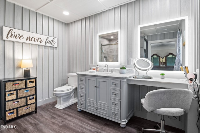 bathroom with vanity, wood walls, a shower with shower door, hardwood / wood-style flooring, and toilet