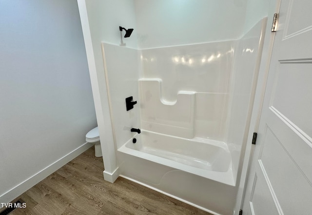 bathroom with wood-type flooring, tub / shower combination, and toilet