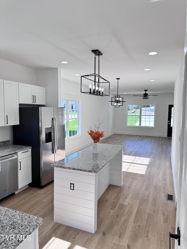 kitchen featuring pendant lighting, stainless steel appliances, a center island, and white cabinets