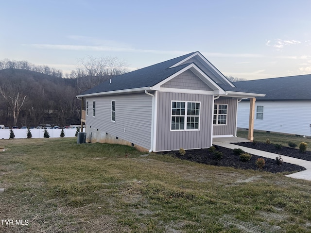 view of side of home with central AC, a lawn, and a water view