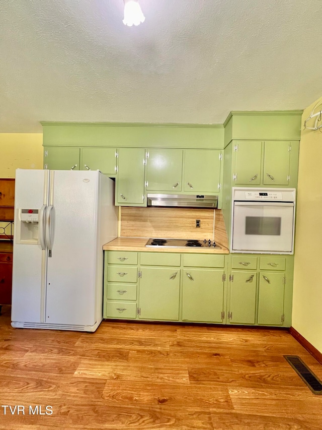 kitchen featuring white appliances, green cabinetry, light wood-type flooring, and ventilation hood