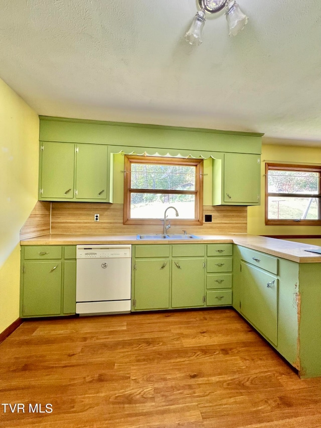 kitchen with dishwasher, green cabinets, sink, a textured ceiling, and light hardwood / wood-style floors