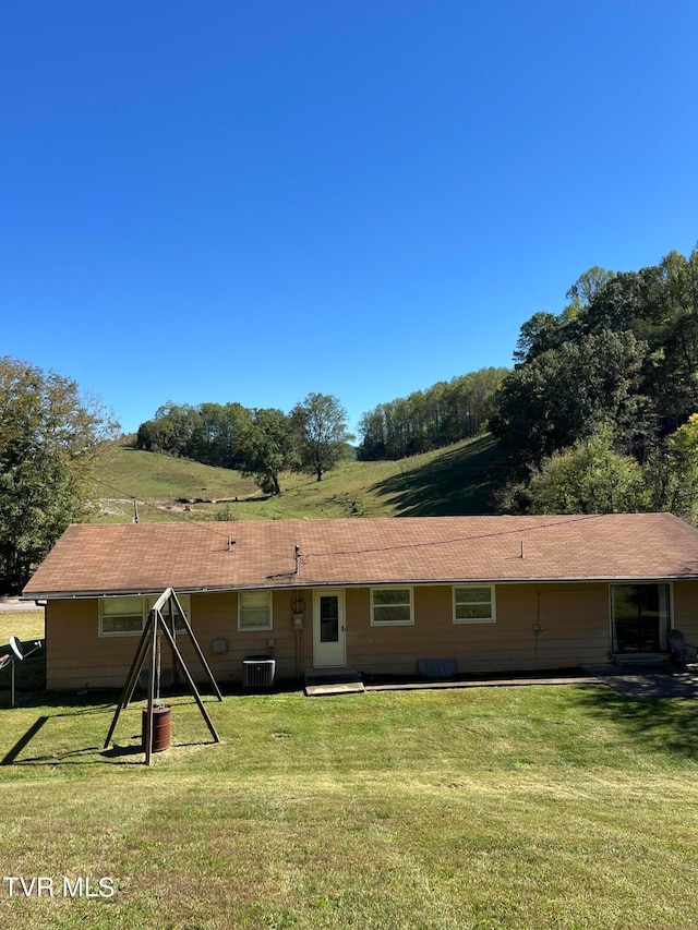 rear view of property featuring a rural view, a lawn, and central AC unit