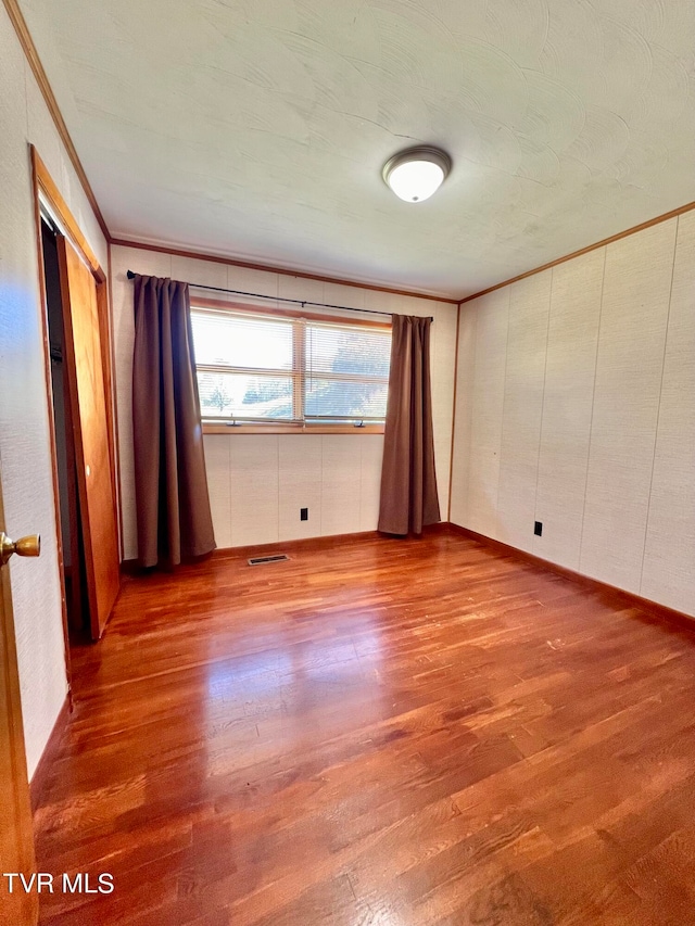 spare room featuring crown molding and light hardwood / wood-style flooring