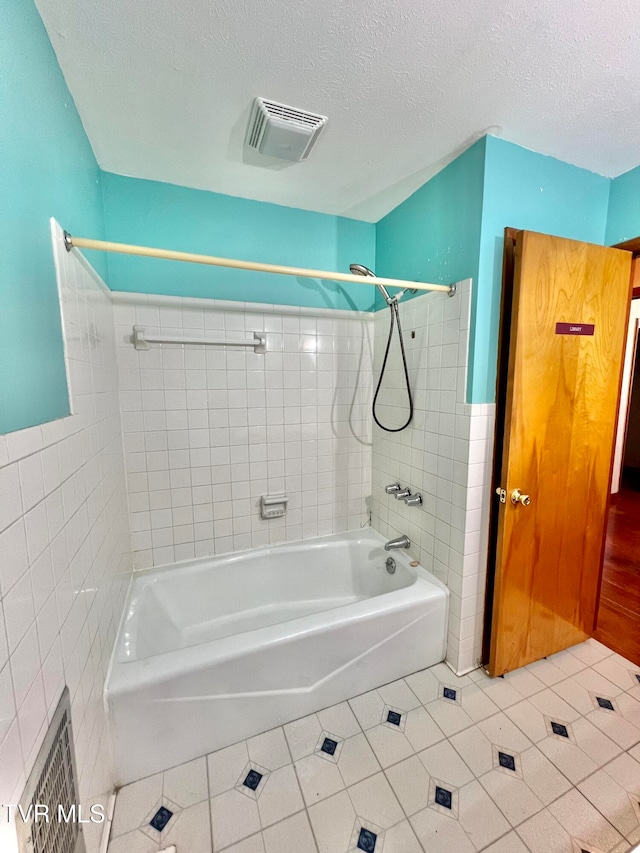 bathroom with tiled shower / bath, tile patterned floors, a textured ceiling, and tile walls