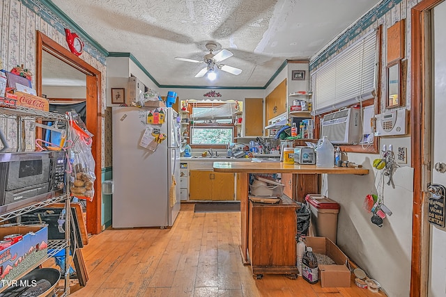 kitchen featuring ornamental molding, white fridge, a textured ceiling, light hardwood / wood-style floors, and ceiling fan