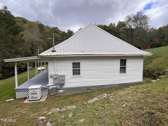 view of property exterior with a yard, a wooded view, and metal roof