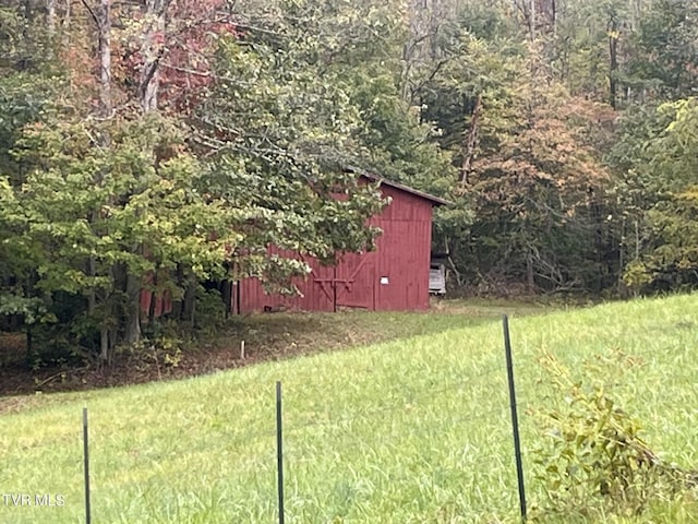 view of yard featuring an outdoor structure and a forest view
