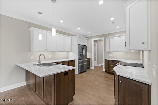 kitchen with white cabinets, stainless steel fridge with ice dispenser, hanging light fixtures, a peninsula, and a sink