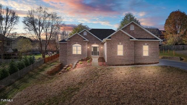 view of front of home with fence, a lawn, and brick siding