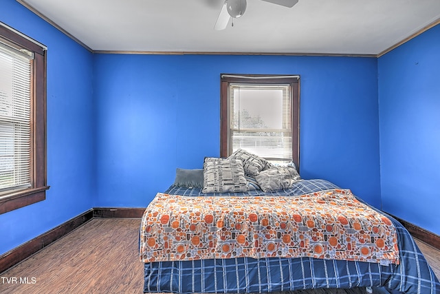 bedroom featuring wood-type flooring, ceiling fan, ornamental molding, and multiple windows