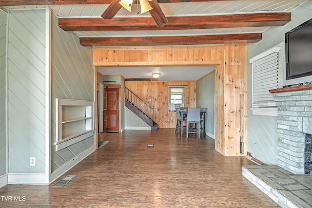 unfurnished living room with beam ceiling, wooden walls, and dark hardwood / wood-style floors